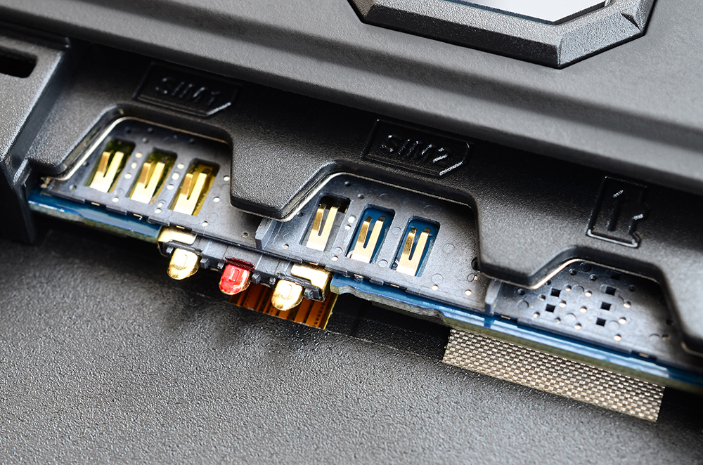 Nahaufnahme eines SIM-Karten- und Speicherkarten-Slots eines elektronischen Geräts. Sichtbar sind mehrere Steckplätze mit goldenen Kontakten, darunter zwei SIM-Schächte und ein SD-Kartenslot. Auch Antennenanschlüsse sind zu sehen.