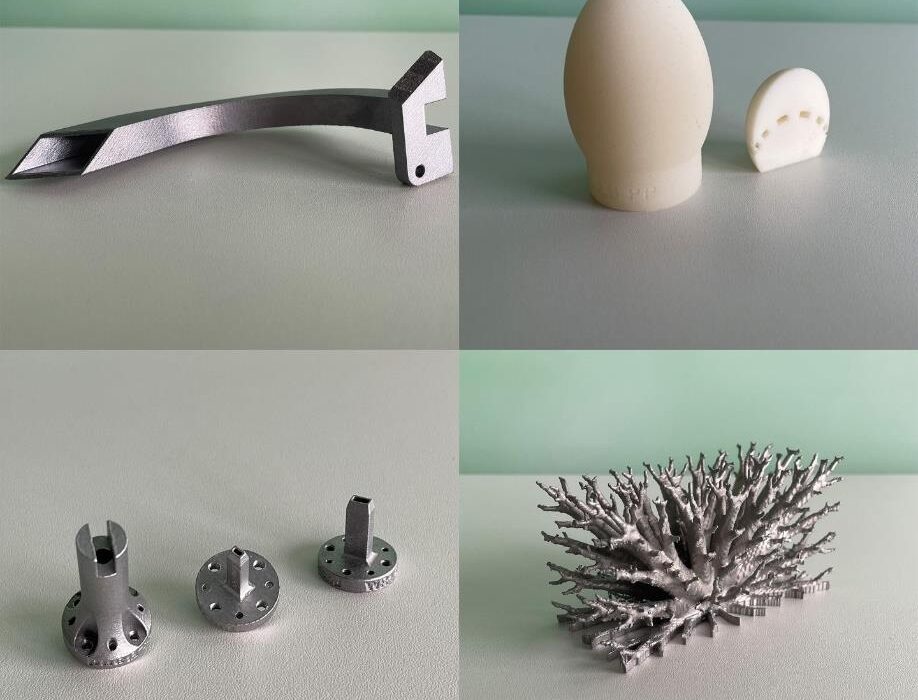 Vier Fotos von unterschiedlich geformten Bauteilen aus dem 3D-Druck, teils aus Metall, teils aus Kunststoff. Die Objekte zeigen komplexe Geometrien, darunter technische Komponenten und eine filigrane, korallenartige Struktur. Alle Objekte liegen auf einer hellen Oberfläche.